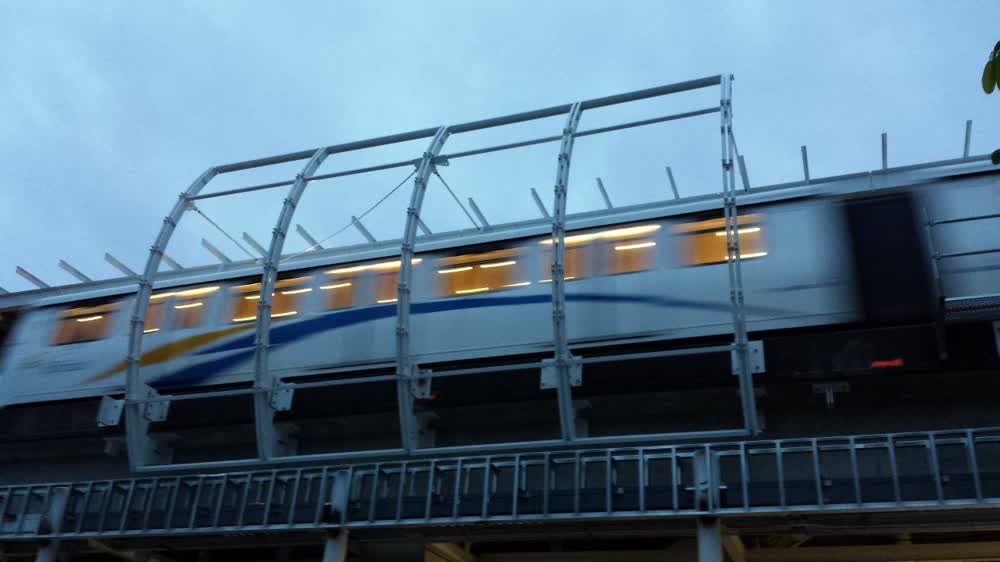 A SkyTrain car in motion behind the curved steel guard structure at Main Street station, Vancouver.