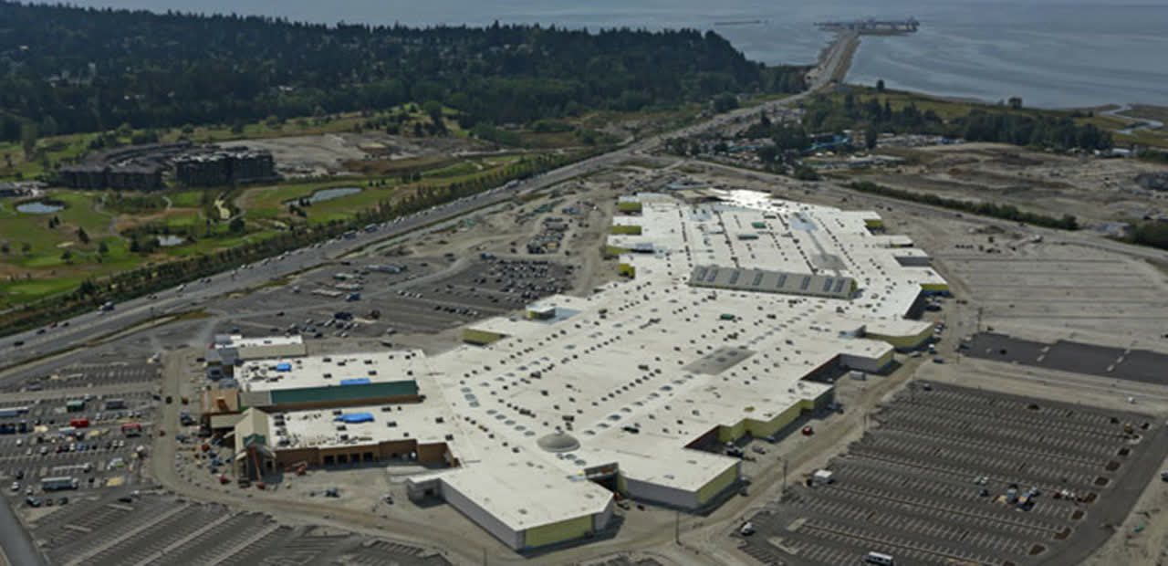 Aerial photograph of the vast Tsawwassen Mills roof under construction, with the Strait of Georgia and the BC Ferries causeway behind it.